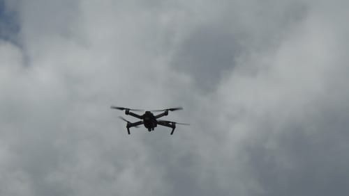 A small unmanned aircraft system in flight against a cloudy sky